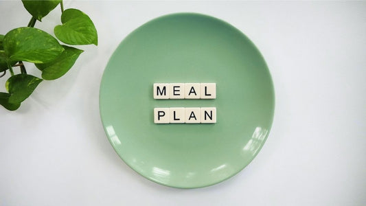 Birdseye view of a green plate with lettering reading 'meal plan'